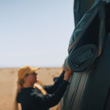 Person in a desert setting with a rolled-up RoofPod awning on a vehicle