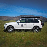 White SUV with RoofPod Awning on a grassy field with mountains in the background