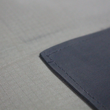 A close up view of an olive and black MEERKAT Shooting Mat, showing the quality of the canvas cover, on a white background