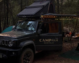 Suzuki Jimny with a rooftop tent in a forest setting, featuring 'CAMP4x4 Rentals'.