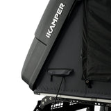 Close-up of a black iKAMPER hardshell rooftop tent on a stargaze mount, showing the side panel with the white iKAMPER logo and a zippered compartment.
