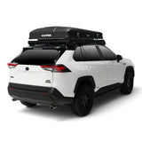 A white SUV shown from the rear three-quarter angle with a black Hardshell iKAMPER Skycamp 4.0 Trio, 3 sleeper, rooftop tent mounted on a black roof rack. The tent has the brand name 'iKAMPER' printed in white on the top panel.