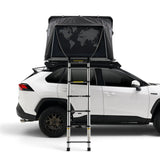 A white SUV shown from the side with an iKAMPER Skycamp 4.0 Trio, 3 sleeper, rooftop top tent mounted above the roof and a metal ladder in front. The tent is dark gray/black with a world map graphic on the front panel.