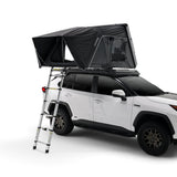 A white SUV with a black Hardshell iKAMPER Skycamp 4.0 Trio, 3 sleeper, rooftop tent and ladder system, shown on a clean white studio background. The tent is fully extended above the vehicle, with a silver metal ladder attached to the rear side for access.